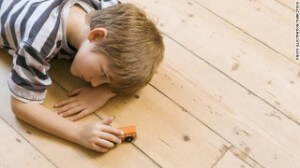 boy with autism laying on floor and playing with truck